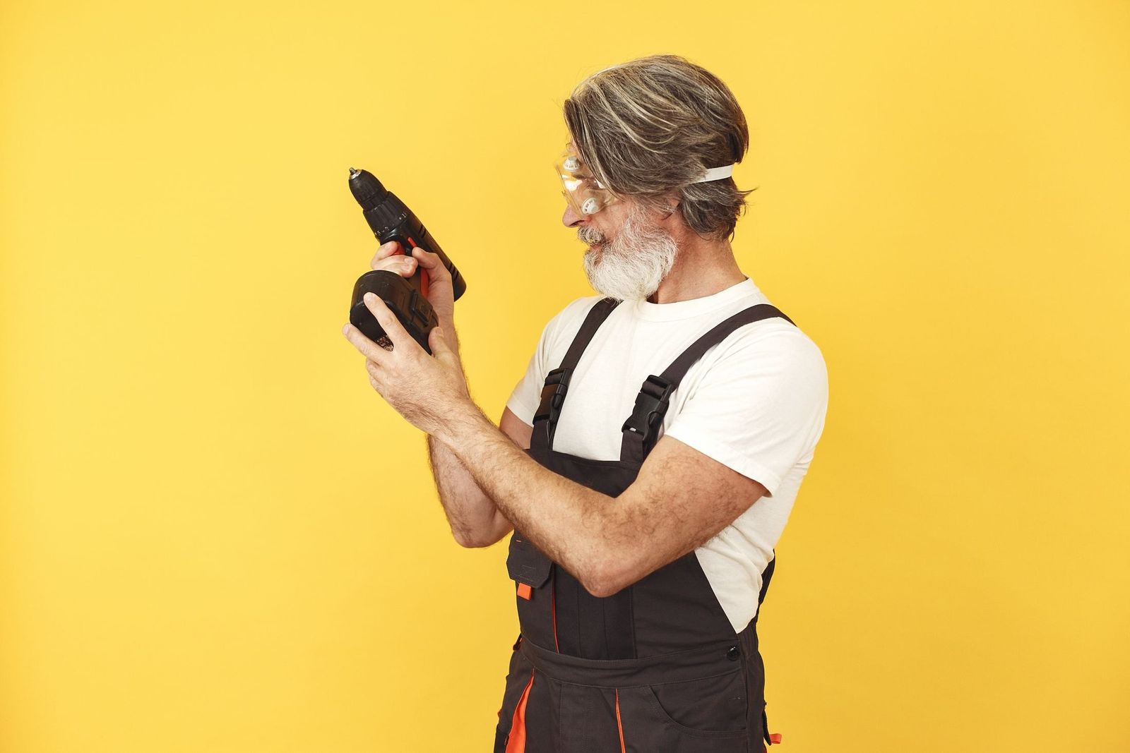 Handwerker in Latzhose prüft die Bohrmaschine