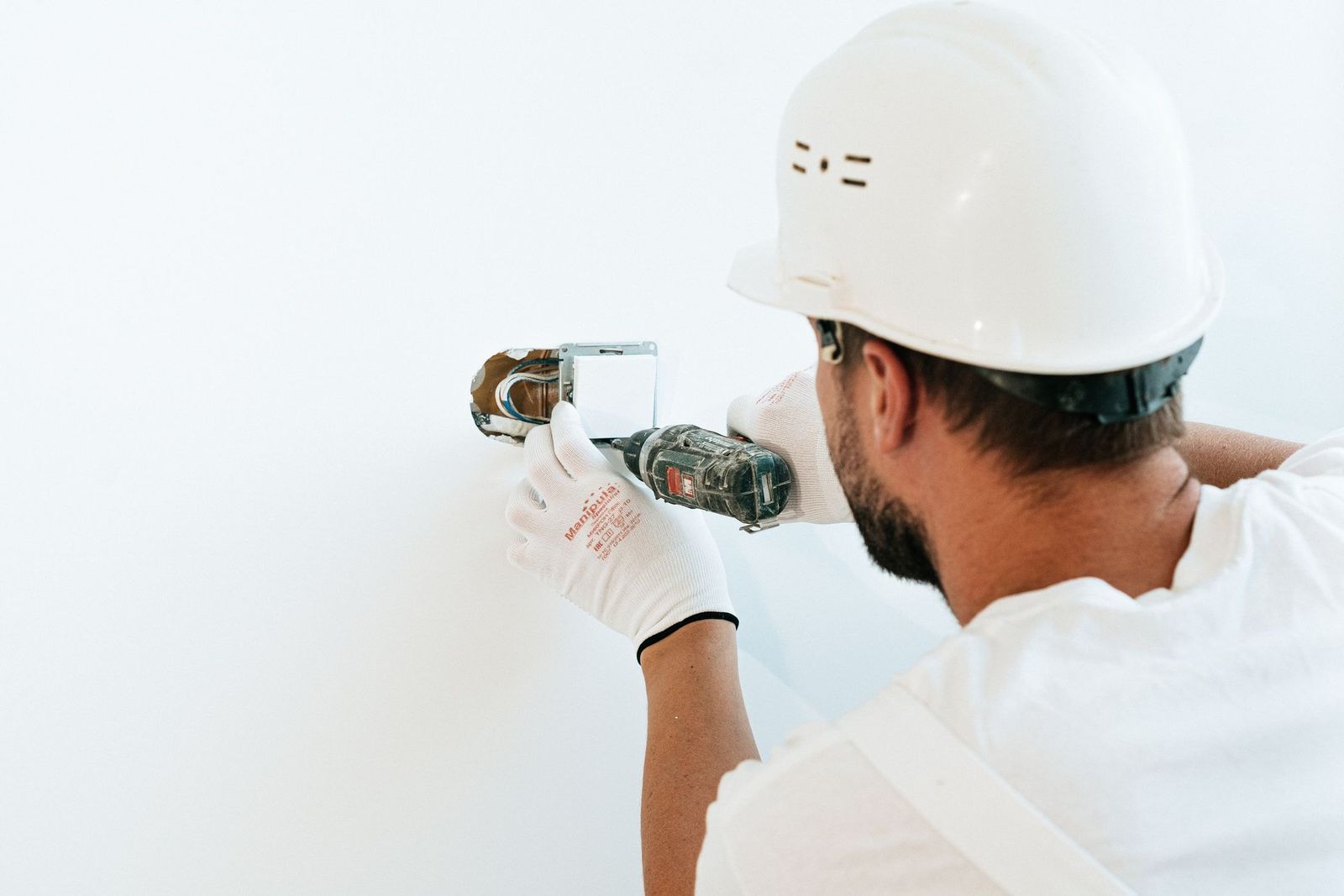 Handwerker mit Helm befestigt etwas an der Wand