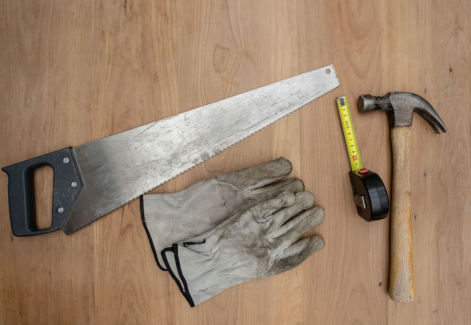 Säge, Hammer und Maßband auf einer Holzfläche